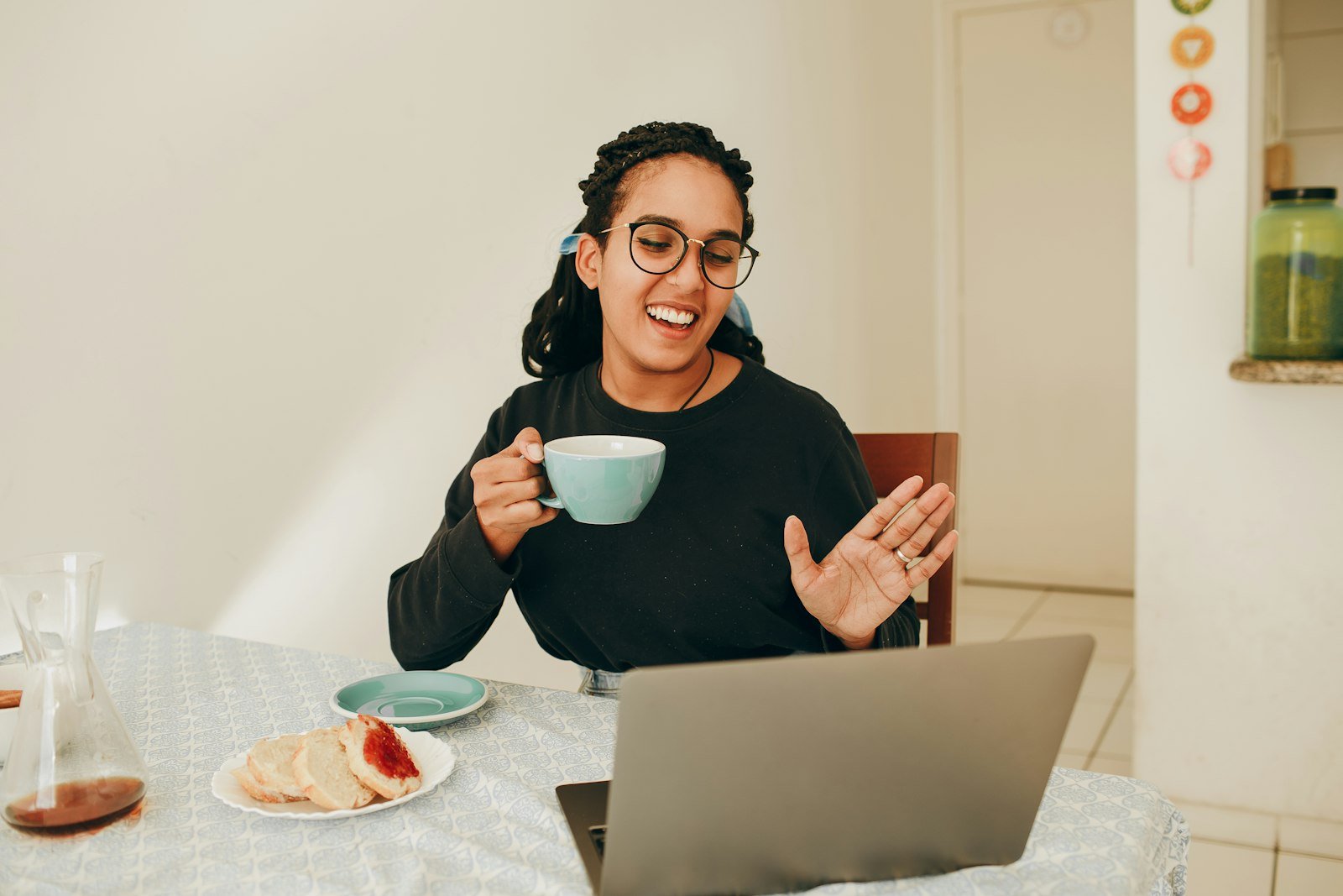 Vrouw met een kop thee in een online coachinggesprek via haar laptop
