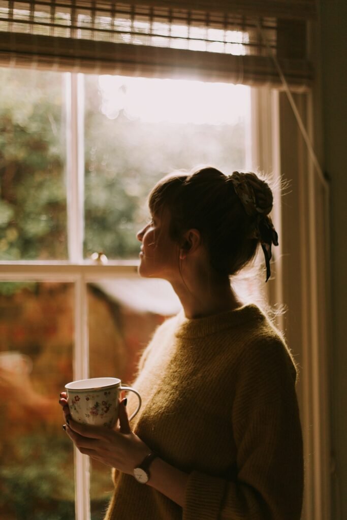 Vrouw met een kop thee kijkt rustig uit het raam